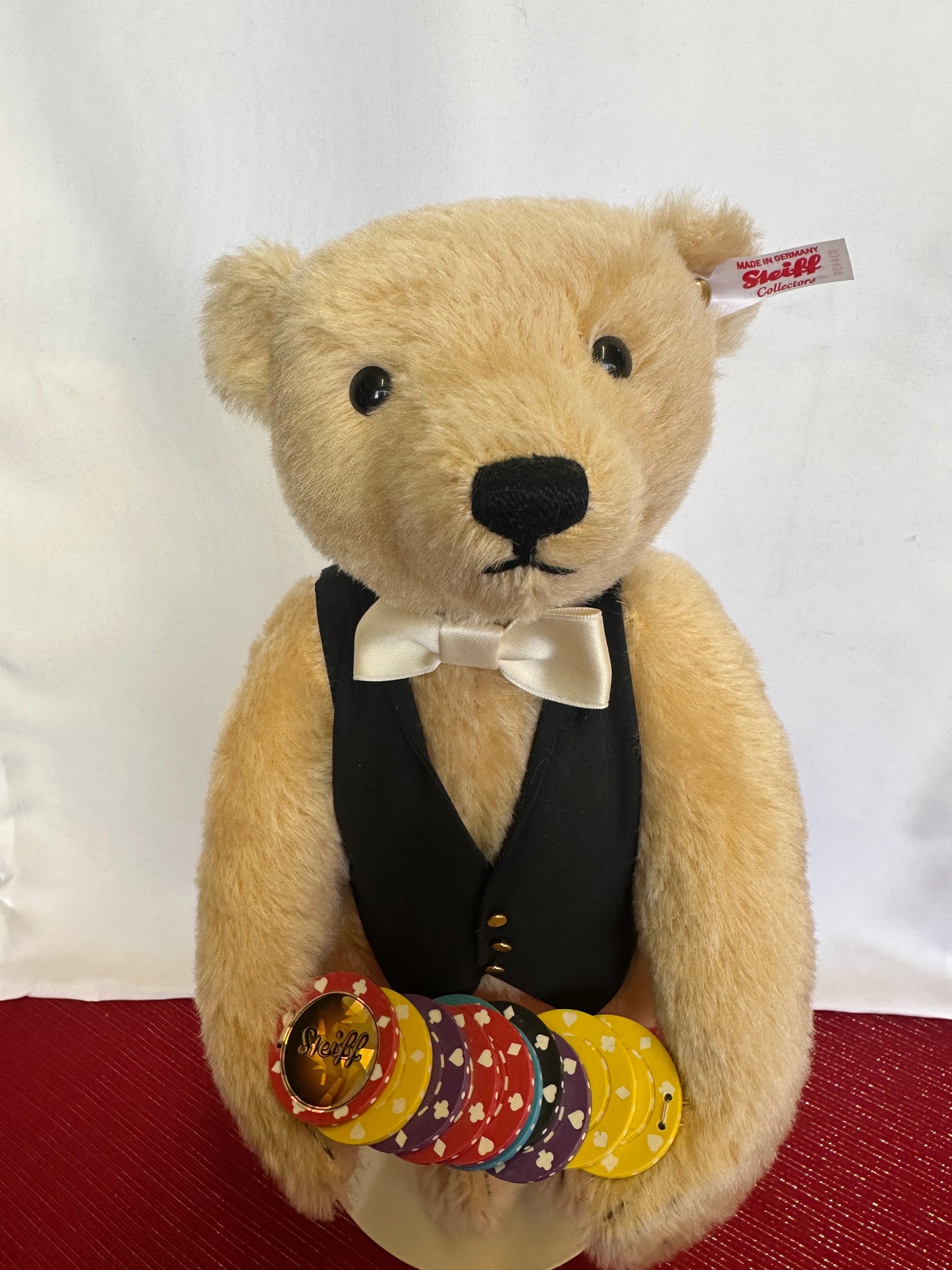 Steiff Croupier teddy bear wearing black vest, bow tie and carrying a stack of chips.  